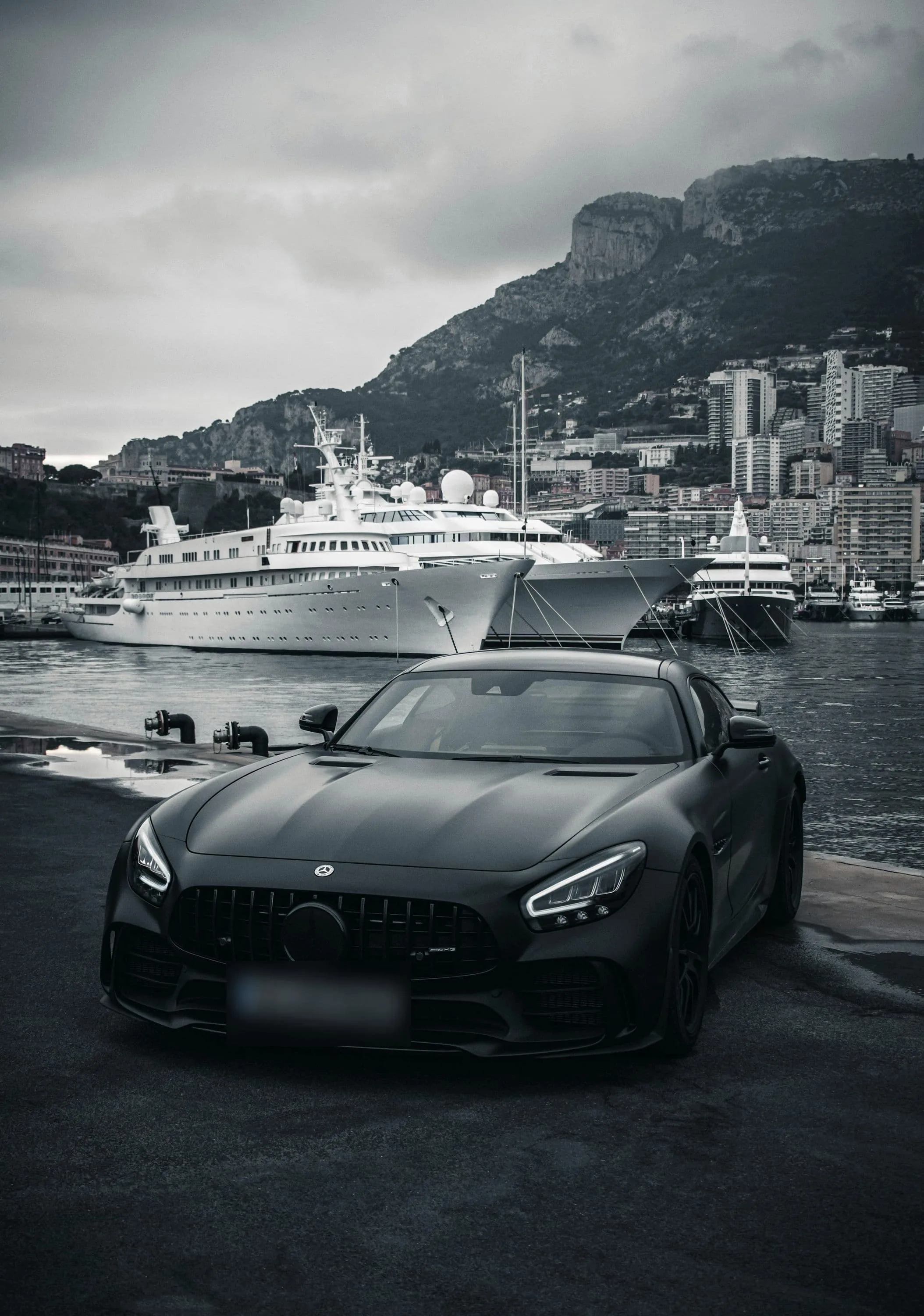 Matte black Mercedes-AMG GT in front of moored superyachts
