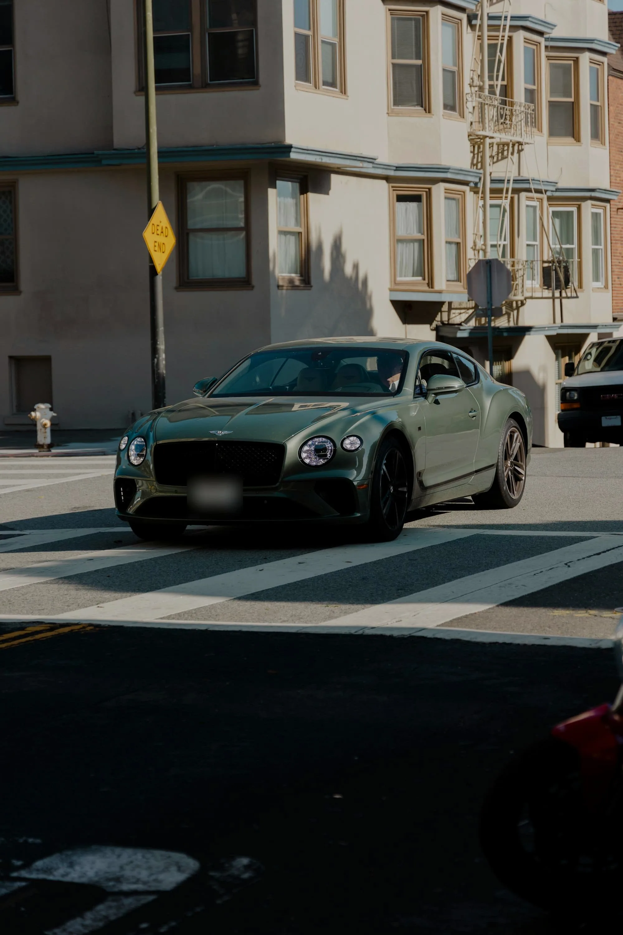 Sage green Bentley Continental GT crossing a pedestrian crossing