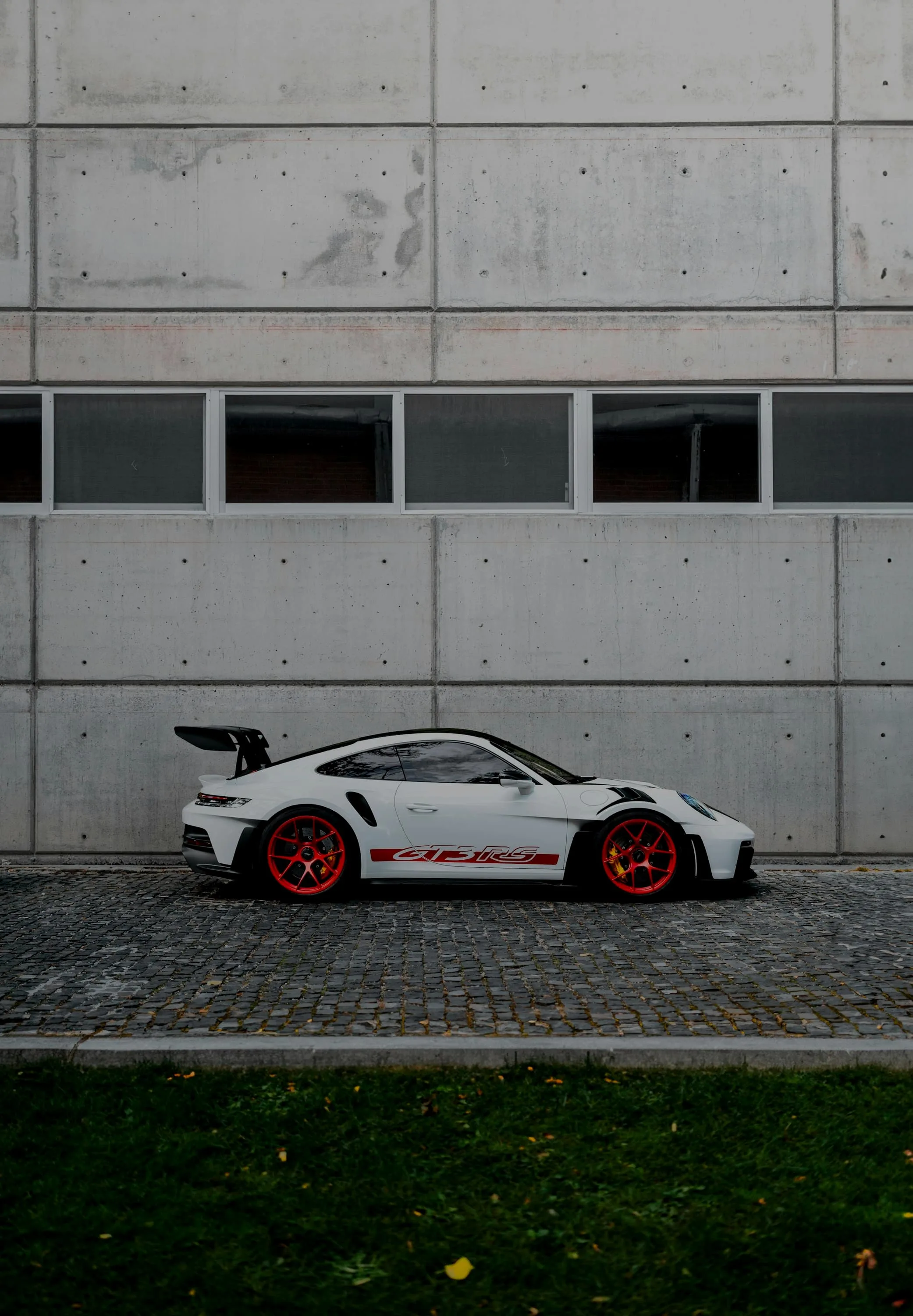 White Porsche 911 GT3 RS in side profile against a concrete wall