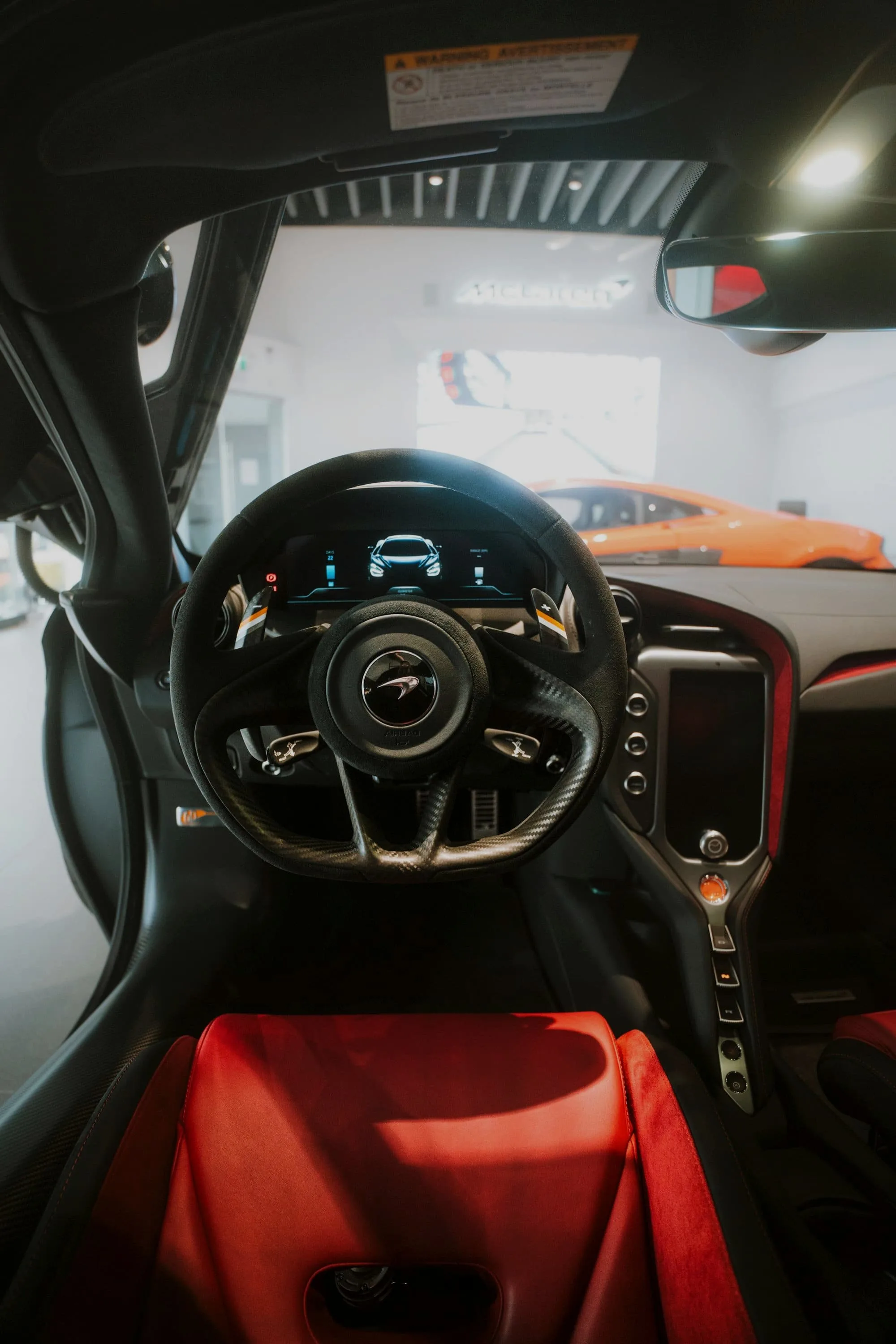 McLaren steering wheel and floating driver display seen through an open door