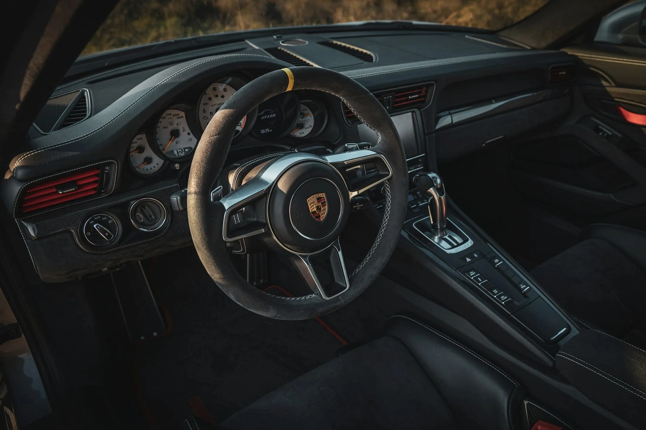 Porsche cockpit with a suede wheel and analogue dials in warm light