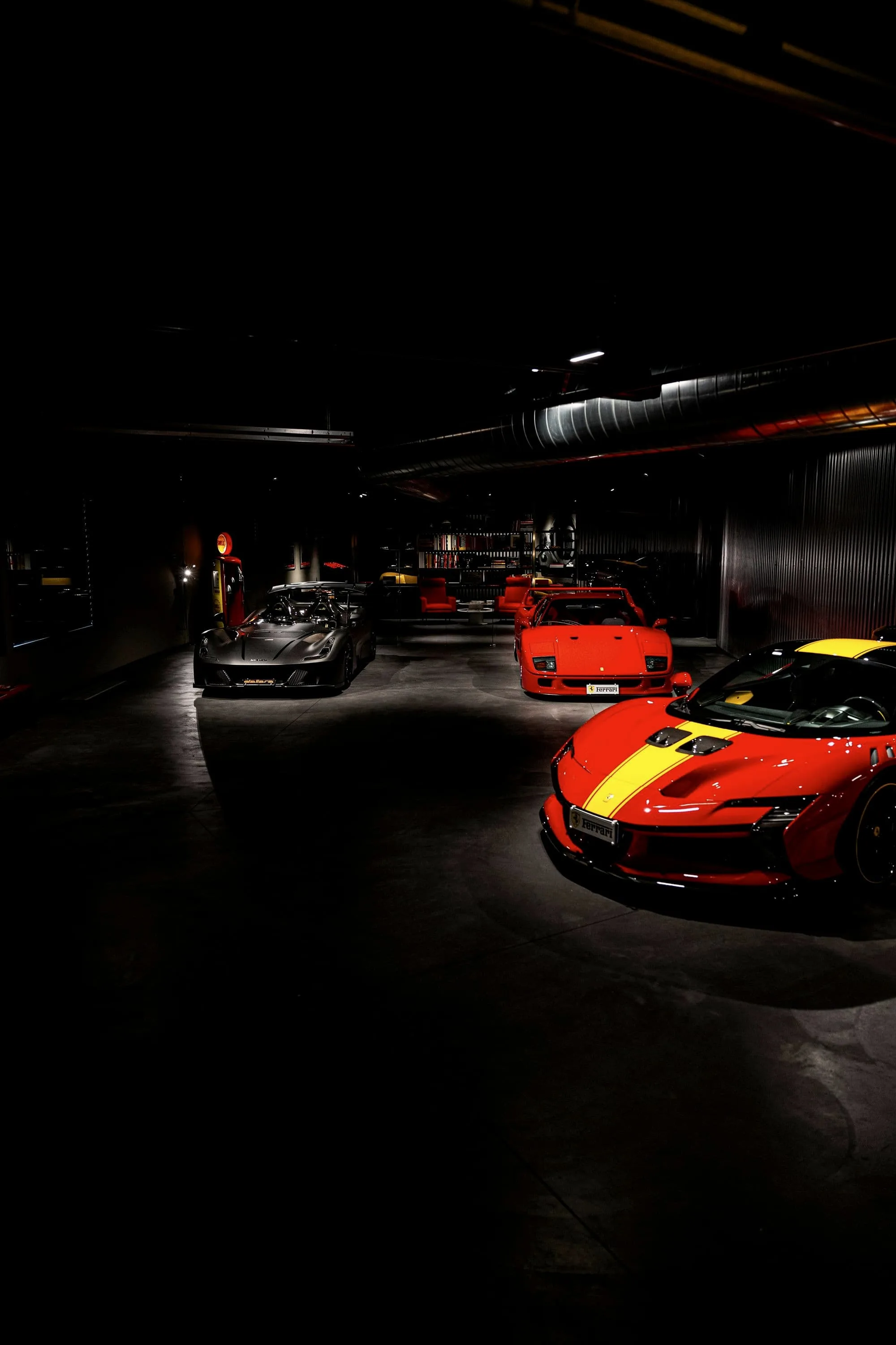 Dark showroom hall with red and silver supercars under low lights