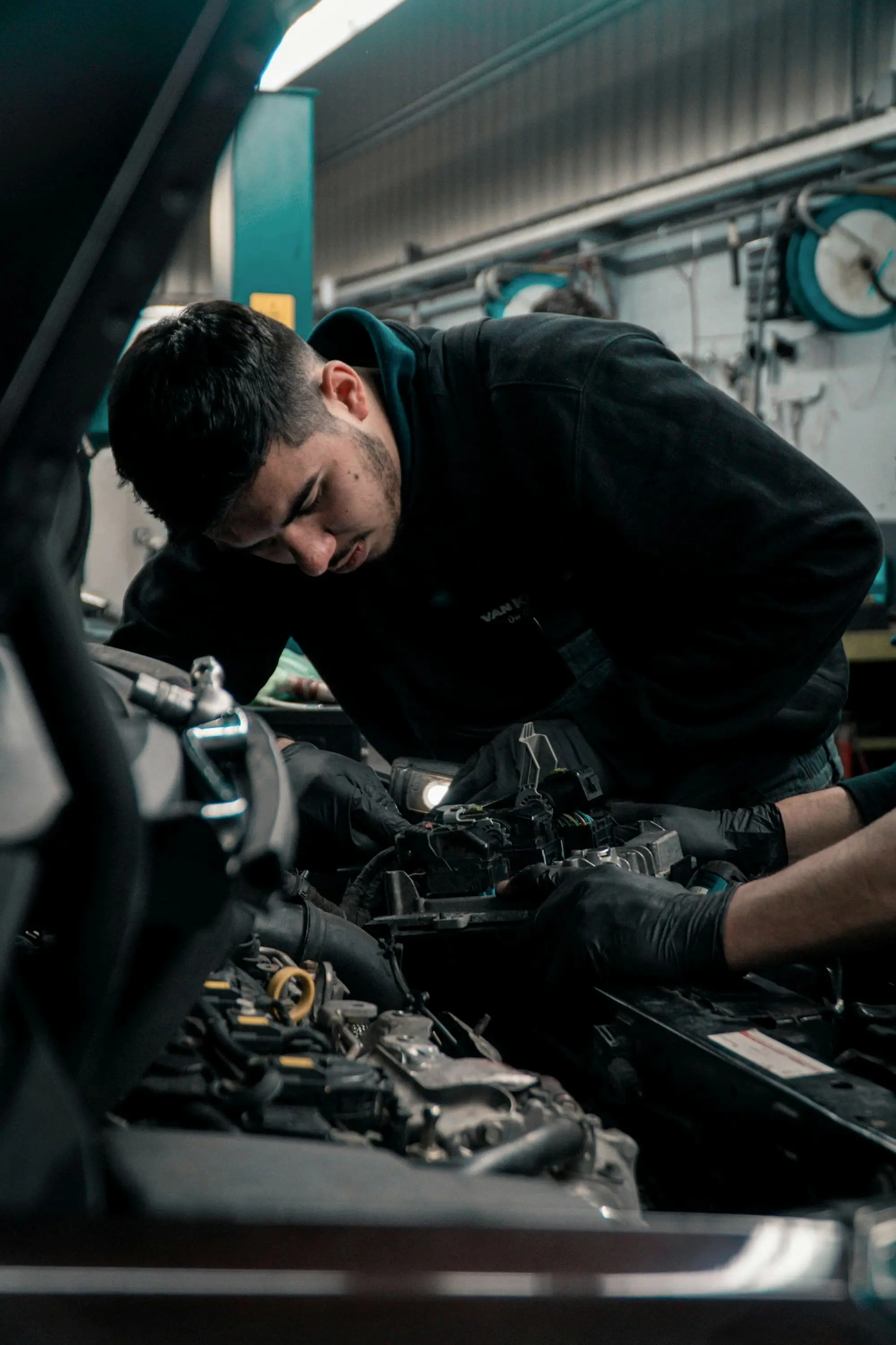 Technician in black working over an engine bay