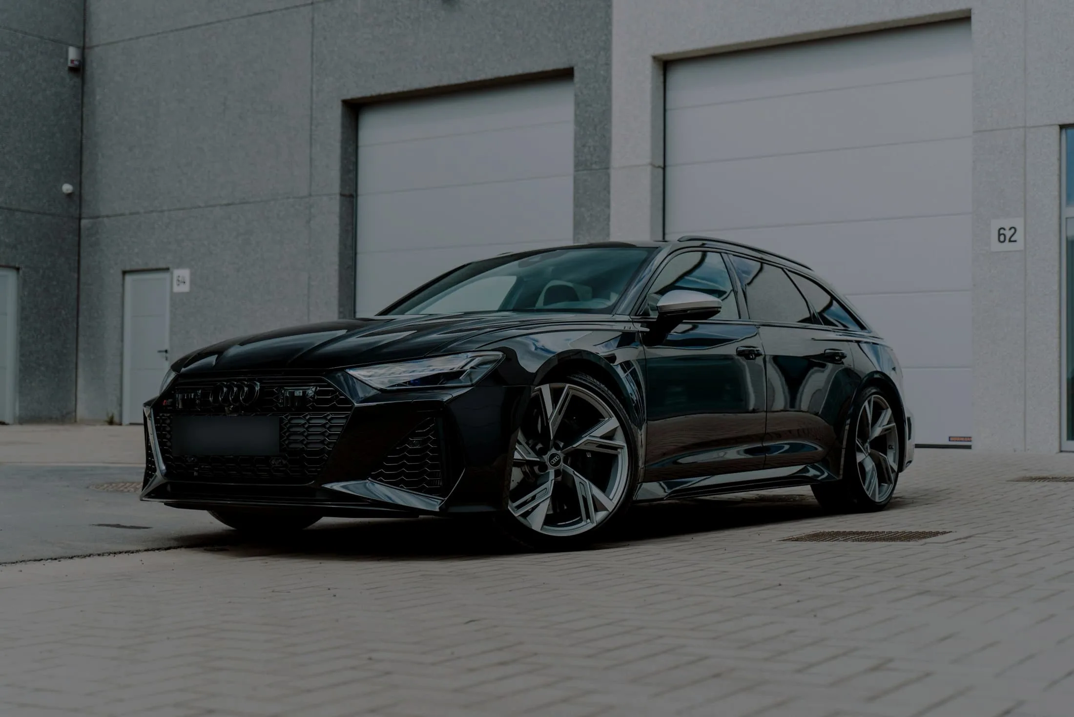 Black Audi RS6 Avant parked on pale paving