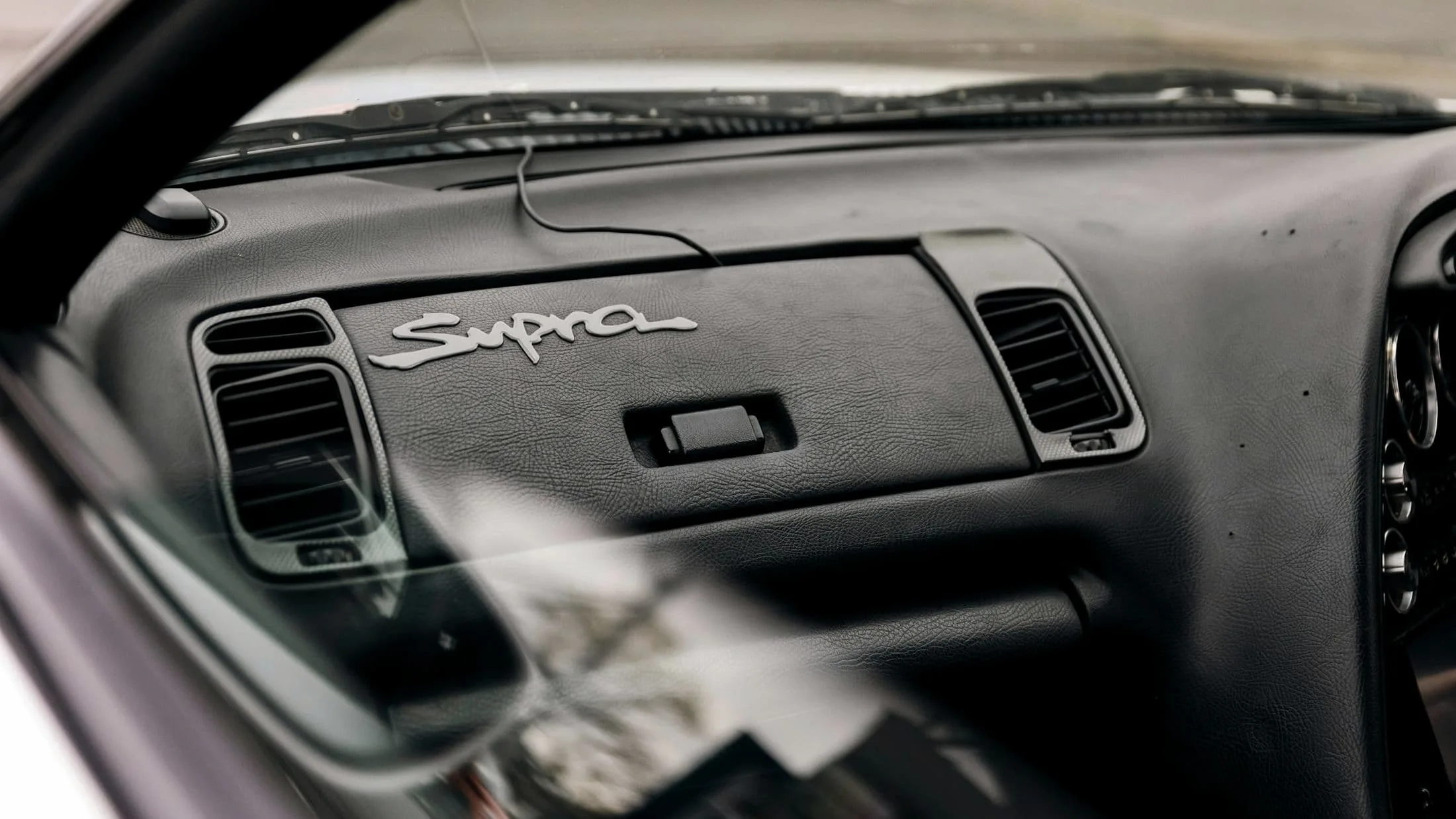 Supra script embossed into a dark leather dashboard